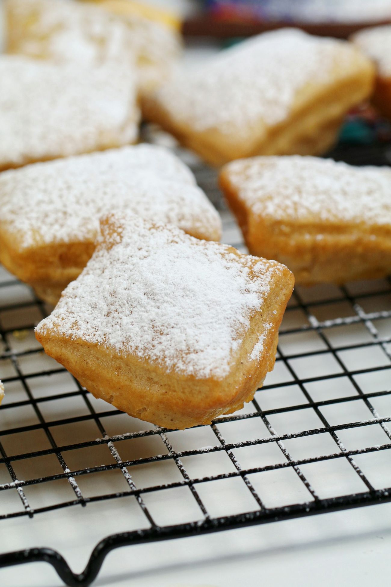 Beignets dusted with powdered sugar on a cooling rack