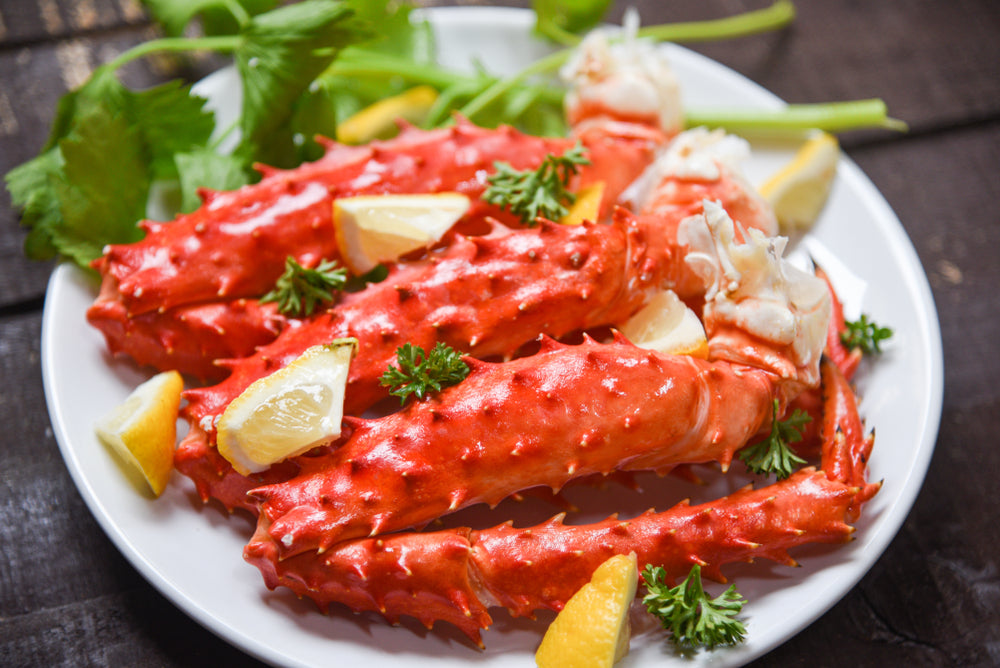 Alaskan King Crab Legs cooked seafood with lemon spices on white plate in the wooden table / red crab hokkaido