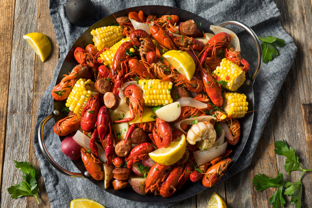 A homemade Southern crawfish boil featuring crawfish, potatoes, sausage, and corn. The ingredients are all cooked together in a flavorful broth, creating a vibrant and appetizing dish. 